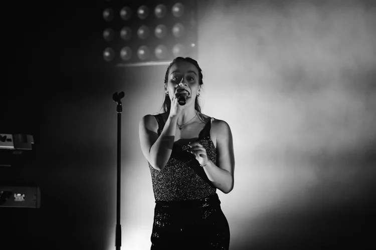 Sangerinde fra Festkompagniet i spotlight, sort-hvid scenefoto. Festkompagniet live som bryllupsband i Thisted, billede 1 af 4.